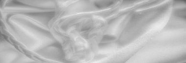 Yumuşak ışıkla yakalanan örülmüş bir iplik içeren bulanık beyaz kumaş. Pürüzsüz yüzey ve karmaşık örgü görüntüye karmaşıklık ve doku hissi verir..