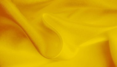 Yüzeyinde örülmüş bir deseni olan yumuşak sarı kumaş bulanıklığı. Yumuşak kıvrımlar ve zarif kumaş ışığı yakalayan yumuşak, akışkan bir doku yaratır..