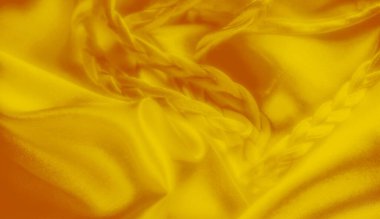 Pürüzsüz, bükülmüş örgüleri olan parlak sarı kumaş bulanıklığı. Lüks saten benzeri kıvrımlar ve zarif doku zengin ve soyut bir görsel kompozisyon oluşturur..