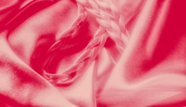 Örgü örülmüş ipeksi pembe kumaşların yakın çekimi büyüleyici bir doku yaratır. Pürüzsüz, parlak madde örülmüş elementin etrafında dolaşarak uyumlu bir kontrast oluşturuyor..