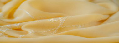 Bulanık - Hassas beyaz işlemeli yumuşak sarı kumaş zarif bir şekilde katlanır, karmaşık çiçekleri ve girdap desenlerini ortaya çıkarır doku zarif ve havadar bir his verir, ışık temalı projeler için mükemmeldir.