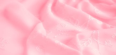 Görüntü. Yumuşak, pembe kumaş, nakışlı detaylar, yumuşak kıvrımlar halinde akıyor. Pürüzsüz yüzey ve karmaşık tasarım görsel olarak çekici bir doku yaratır..