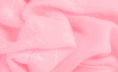 Karmaşık işlemeli yumuşak pembe kumaş bulanıklığı. Kumaşın nazik akışı zarif ve pürüzsüz bir doku yaratıyor, narin işçiliğini sergiliyor..