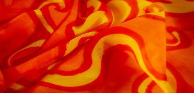 Kıvrımlı sarı desenli canlı turuncu kumaş, pürüzsüz kıvrımlar ve kumaş dokusunda hareket ve derinlik hissi yaratan karmaşık kıvrımlar..