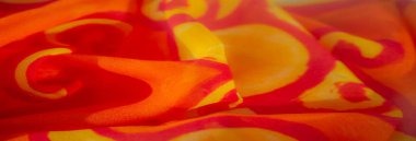 Canlı turuncu ve sarı kumaşlı kıvrımlı bulanık, enerjik ve dinamik bir görsel etki yaratıyor. Kumaş katlanmış, maddedeki ışık ve dokunun etkileşimini gösteriyor..