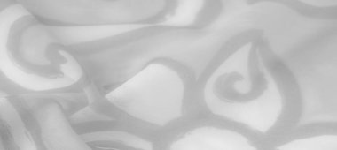 Girdap gibi gri motifleri olan beyaz kumaşın bulanık görüntüsü yumuşak bir parıltıyla hafif bir akış yaratıyor. Işık ve gölgenin etkileşimi derinlik ekler, pürüzsüz dokusu ise havadar zarafetini arttırır..