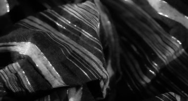 Bulanık, zarif dikey çizgileri olan yumuşak kumaş. Karmaşık kıvrımlarla ışığı yakalıyor. Siyah ve beyaz tonlar, modern moda ve tasarım için mükemmel, pürüzsüz, parıldayan bir doku yaratır..