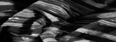 Örülmüş siyah kumaş yumuşak kıvrımlar ve parlak bir yüzey sergiliyor. Işığı ince bir şekilde yansıtıyor. Bu lüks tekstil her tasarıma biraz cazibe katar..