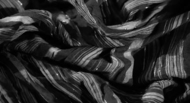 Görüntü: Katlanmış siyah bir kumaşın, dokulu ve parlak aksanlı bir görüntüsü, parıltılı bir etki yaratır. Karmaşık dokuma ve narin parıltı kumaşa lüks bir hava katıyor.