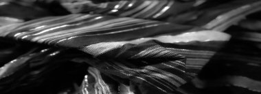 Örülmüş dokusu ve zarif parlak elementleriyle parıldayan siyah kumaş pürüzsüz kıvrımlarını ve sofistike parlaklığını vurgulamak için zarifçe örtülmüş.