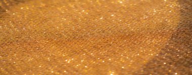 Zengin bronz tonlarda parıldayan kumaşın yumuşak odak görüntüsü. Narin dokular ve ışıl ışıl renkler lüks ve zarif bir estetik yaratıyor..