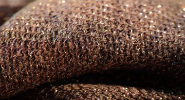 Yüzeyinde karmaşık bir parıltı olan parlak kahverengi kumaş bulanıklığı. Kumaş, ışığı yumuşak bir ışıltıyla yansıtıyor, malzeme dokusu ve tasarımı sergiliyor. Zarif, ışıltılı detaylar göze çarpıyor.