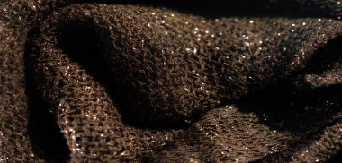 Karmaşık dokuma dokusuyla parıldayan kahverengi kumaşın bulanıklığı ve parlak gölgeler. Parlak iplikler lüks bir his yaratıyor, malzemeye derinlik ve yumuşaklık katıyor..