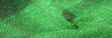 Işıl ışıl yeşil kumaş ve detaylı bir dokuma. Işıl ışıl iplikleri yakalıyor ve canlı bir yüzey oluşturuyor. Karmaşık desenler ışığı yansıtıyor, lüks dokusunu geliştiriyor..