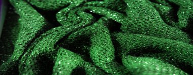 Işıldayan beneklerle süslenmiş canlı yeşil kumaş bulanıklığı, yumuşak odaklı dokulu bir yüzey gösteriyor, arka plan veya materyal odaklı projeler için mükemmel