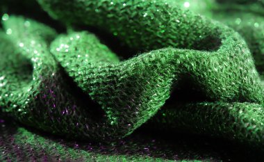 Işıldayan yeşil kumaş yüzeyinin bulanık görüntüsü derin doku ve ışık altında parlayan parlak yansıtıcı ışıltılar büyüleyici bir etki yaratıyor..