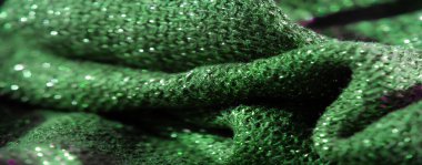 Işıldayan yeşil kumaş yüzeyinin bulanık görüntüsü derin doku ve ışık altında parlayan parlak yansıtıcı ışıltılar büyüleyici bir etki yaratıyor..