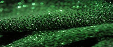 Büyüleyici bir makro yeşil parıltılı kumaş, dokunmuş dokuyu ve parıltılı parıltıyı aydınlatan. Dokulu yüzeydeki ışığın etkileşimi görüntüye derinlik katar.