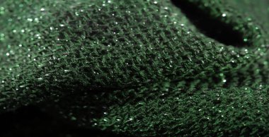 Parlak yeşil kumaşın bulanık görüntüsü ve karmaşık sim dokusu. Titrek yüzey ışığı yansıtıyor, kumaşın detaylı dokumasını ve parıldayan kalitesini vurguluyor..