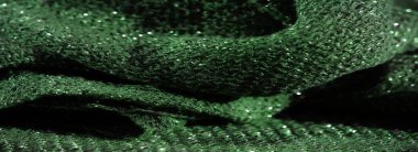 Parlak bir dokusu ve karmaşık dokuması olan yeşil parıltılı kumaşın bulanık görüntüsü. Parlak, parlak bir tekstil etkisi yaratmak için ışık yansıtan bir madde..