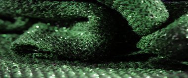 Parlak detaylarla dolu canlı yeşil kumaşın bulanık görüntüsü. Parlak yüzey ve narin dokuma deseni maddenin zenginliğini vurgulayan parlak bir doku yaratır..