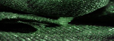 Parlak yeşil kumaşın bulanık görüntüsü ve karmaşık sim dokusu. Titrek yüzey ışığı yansıtıyor, kumaşın detaylı dokumasını ve parıldayan kalitesini vurguluyor..