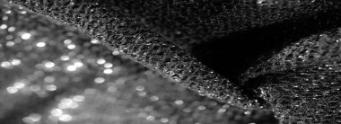 Parlak siyah kumaşın bulanık görüntüsü, yumuşak ve parıltılı dokuma dokularını sergiliyor. Makro çekim kumaşın yüzeyini parlak bir kaplamayla vurguluyor..