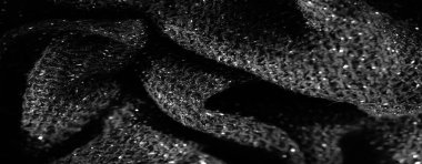 Görüntü - ince dokular ve parlak elementler gösteren parlak siyah kumaşların makro çekimi. Karmaşık kumaş deseni ince kıvrımlar ve ışığı yansıtan göz kamaştırıcı bir yüzey içeriyor.