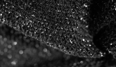 İnce parıltılı siyah kumaş bulanıklığı. Karmaşık bir desen oluşturuyor. Detaylı doku, çekime zarafet ekleyerek materyalin ışıltısıyla vurgulanır..