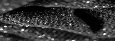 Işıldayan röflelerle siyah kumaşın bulanık görüntüsü ışıl ışıl bir etki yaratıyor. Karmaşık dokuma ışığı küçük yansıtıcı noktalarda yakalar ve parlak bir görüntü verir..