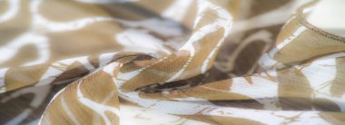 Bulanık yumuşak, şeffaf bir dokusu olan açık kahverengi kumaş hassas dalgalar halinde akar, rahatlatıcı bir toprak tonu ve beyaz çizgiler oluşturur. Kumaş kıvrımları pürüzsüz yüzeyini vurgular