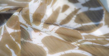 Bulanık yumuşak, şeffaf bir dokusu olan açık kahverengi kumaş hassas dalgalar halinde akar, rahatlatıcı bir toprak tonu ve beyaz çizgiler oluşturur. Kumaş kıvrımları pürüzsüz yüzeyini vurgular