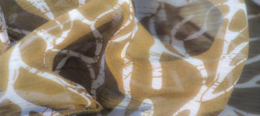 Görüntü, soyut beyaz yaprak benzeri tasarımları olan açık kahverengi bir kumaş. Kumaşlar ona organik bir akış sağlıyor, karmaşık ve dokulu bir görünüm yaratıyor..