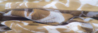 Kahverengi ve beyaz çizgili yumuşak kumaş bulanıklığı. Karmaşık bir şekilde doğal kıvrımlara sarılmış. Kumaşın saf kalitesini vurgulayan organik ve hassas bir doku sağlıyor..