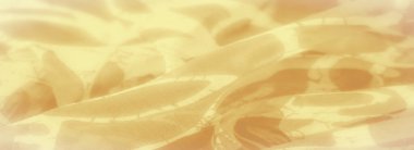 Pürüzsüz ve soyut desenleri olan akışkan sarı kumaş bulanıklığı, sakin ve zarif bir tasarım yaratıyor. Kumaş kıvrılır ve yumuşak odaklanma hareket ve sıcaklık izlenimi verir..