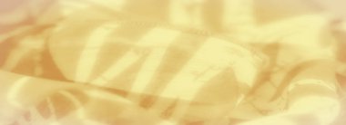 Narin kıvrımları ve üzengiyi andıran ince desenleri olan yumuşak sarı bir kumaş bulanıklığı. Kumaş boyunca yayılan ışık, zarafetini artırmak için ılık ve yumuşak bir parıltı ekler..