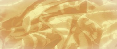 Soyut üzengi desenli sarı kumaş bulanıklığı, yumuşak kıvrımlar ve doku oluşturmak için yavaşça buruşmuş. Yüzeyden yansıyan ışık karmaşık detayları vurgular.