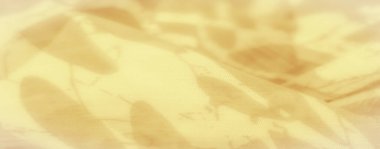 İnce üzengimsi desenli sarı kumaşın bulanık görüntüsü. Kumaşlar pürüzsüz doku ve nazik kıvrımlar, zarif tekstil tasarımları için mükemmel, görsel olarak yumuşak ve sakinleştirici bir etki yaratır..
