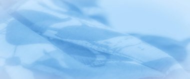 Bulanık, bu resim düz yüzeyinde dokuduğu kıvrımlı soyut şekilli açık mavi kumaşı gösteriyor. Akan kıvrımlar ve yumuşak doku bir huzur yaratır.,