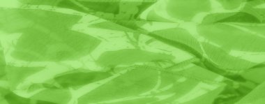 Soyut beyaz desenli bulanık yeşil kumaş yumuşak dalgalar yaratıyor. Kumaş hafif ve şeffaf görünüyor, yumuşak kıvrımlar ve kıvrımlar halinde akıyor, tasarımın organik hissini arttırıyor..