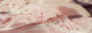 Bulanık pembe saten kumaş. Karmaşık bir dantelle eşleştirilmiş. Romantik bir estetik için pürüzsüz saten ve ayrıntılı bağcıklar arasındaki etkileşimi yakalıyor.
