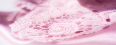 Görüntü pürüzsüz satenin üzerine örtülmüş pembe dantelin sanatsal yakın plan çekimi, narin çiçek desenlerini ve ayrıntılı işçiliğini vurguluyor. Görüntü kadınsı ve lüks bir his yaratıyor..