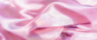 Yumuşak ve ipeksi pembe bir kumaş, yumuşak, akışkan kıvrımlar halinde yakalanır. Yüzey ışığı bir şekilde yansıtır. Lüks ve ışıltılı dokuyu güçlendirir ve narin ama göz alıcı bir görsel etki yaratır.