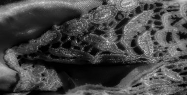 Yumuşak, organik dalgalarda yavaşça çağlayan pürüzsüz saten bir kumaşın gri tonda bir görüntüsü. Kumaşların yüzeyi ışığın altında parlıyor ve narin dokuyu vurgulayan parlak bir etki yaratıyor..