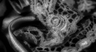 Hafif kıvrımlı parlak saten kumaşın siyah bulanıklığı ışık maddenin pırıltısını ve pürüzsüzlüğünü arttırır, ışık ve gölgenin etkileşimini oluşturur, bu da lüksüne dokuma ve derinlik katar.