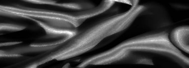 Yumuşak kıvrımları ve pürüzsüz dokuları olan saten kumaştan siyah bir Blur. Saten, yumuşak ışık altında parıldıyor ve maddenin yüzeyinde büyüleyici bir ışık ve gölge etkileşimi yaratıyor.