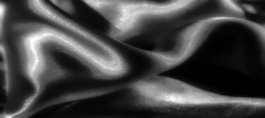 Siyah bulanık, gri tonda katlanmış saten kumaş, yansıtıcı, parlak yüzeyi ışığı yakalıyor. Pürüzsüz, lüks dokusu vurgulanıyor, yumuşak bir...