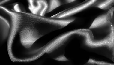 Yumuşak kıvrımlı siyah bulanık, parlak, saten kumaş. Gri tonlu soyut bir yakın plan içinde ışığı ve gölgeyi yakalıyor. Lüks, pürüzsüz bir doku ekliyor.