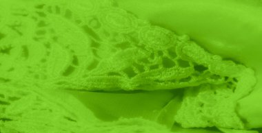 Canlı yeşil bir dantelin bulanıklığı ve karmaşık detaylarıyla kumaş tekstili. Yumuşak kıvrımlar hassas dantel desenine kusursuz bir şekilde karışır, yumuşak ve zarif bir doku yaratır.