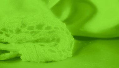 Yumuşak, dalgalı yeşil kumaşlı, ön planda karmaşık dantel detaylarıyla. Yumuşak tekstil ve ince dantel desenlerinin birleşimi zarif ve parlak bir görünüm yaratır..